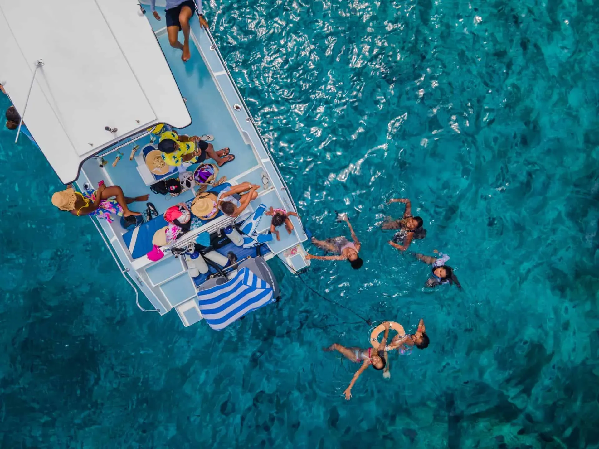 A group of people enjoying a boat excursion with some swimming in the crystal-clear turquoise waters of Seychelles.
