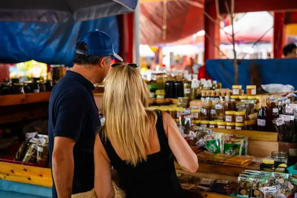 A couple browsing vibrant stalls filled with spices, preserves, and local products at a market in Seychelles.
