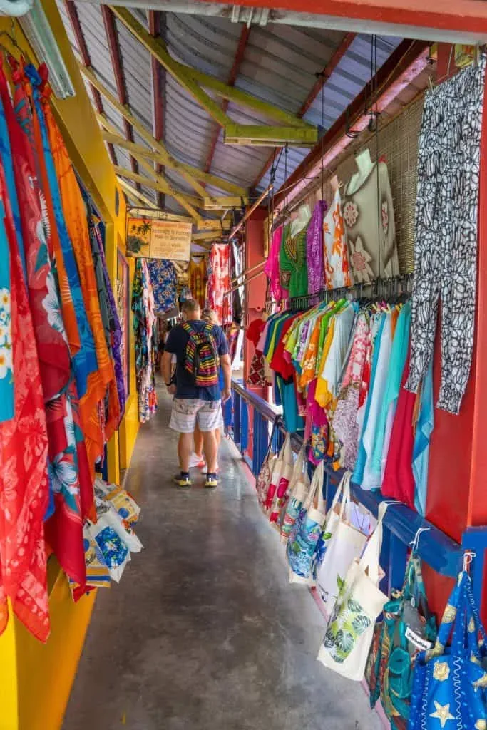Tourists browsing colorful market stalls filled with fabrics, bags, and handcrafted goods in Seychelles.