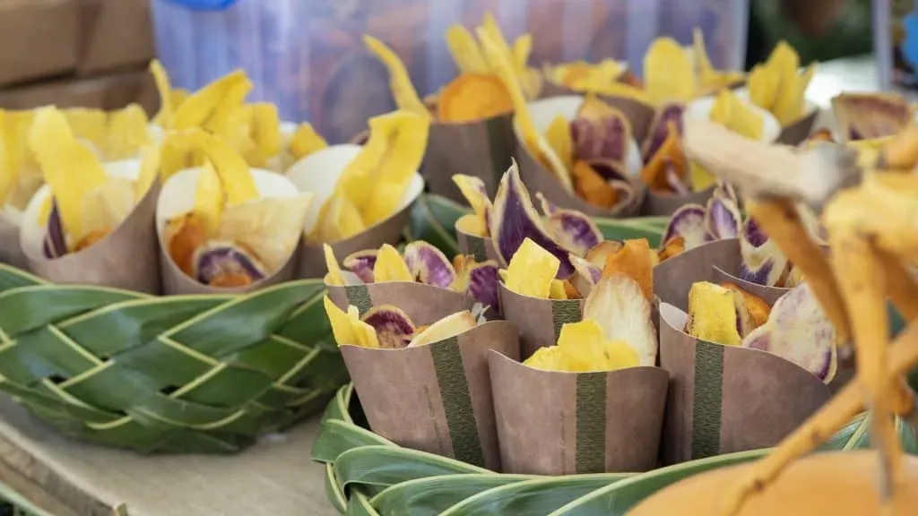 A display of sweet potato and banana chips served in eco-friendly paper cones, arranged in woven palm baskets at a market in Seychelles.
