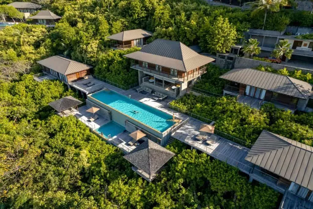 Aerial view of luxury villas nestled in lush greenery with an infinity pool overlooking the tropical landscape in Seychelles.