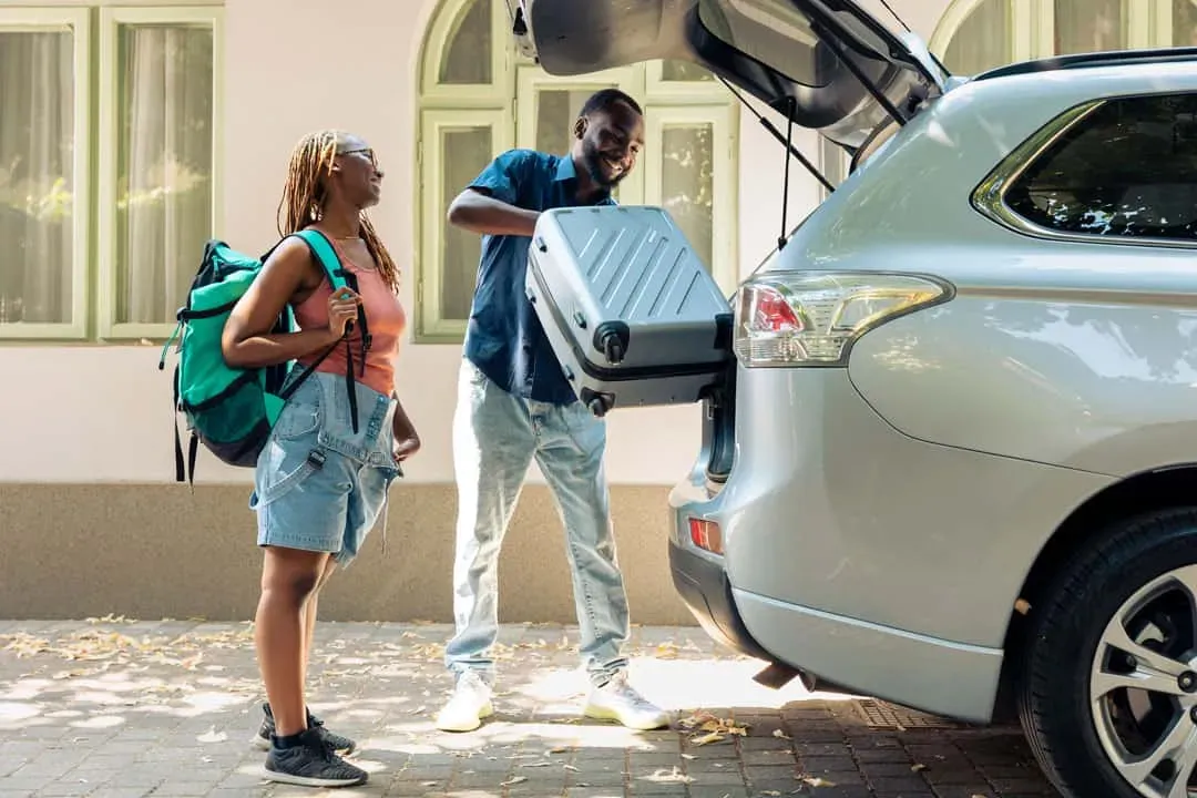 Smiling couple loading luggage into the trunk of a silver SUV, getting ready for a holiday in Seychelles.