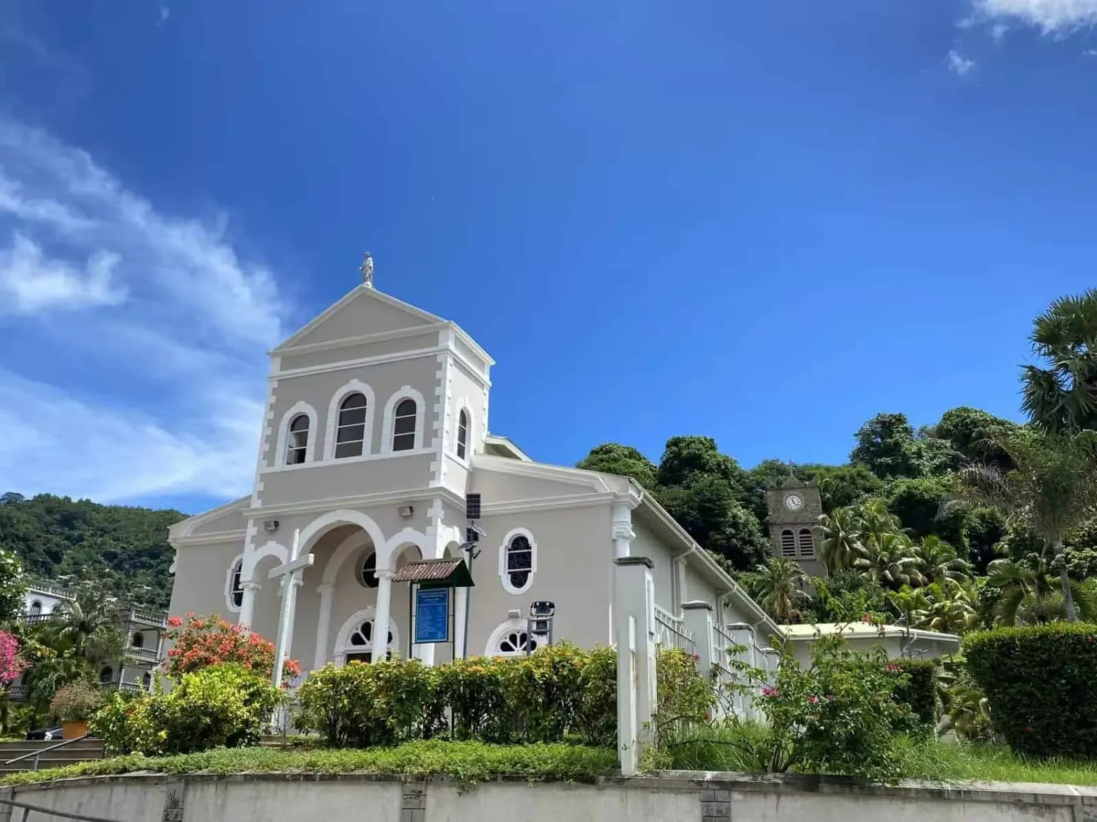 Chapel on a lush hillside with vibrant flowers and greenery, under a clear blue sky in Victoria, Seychelles.