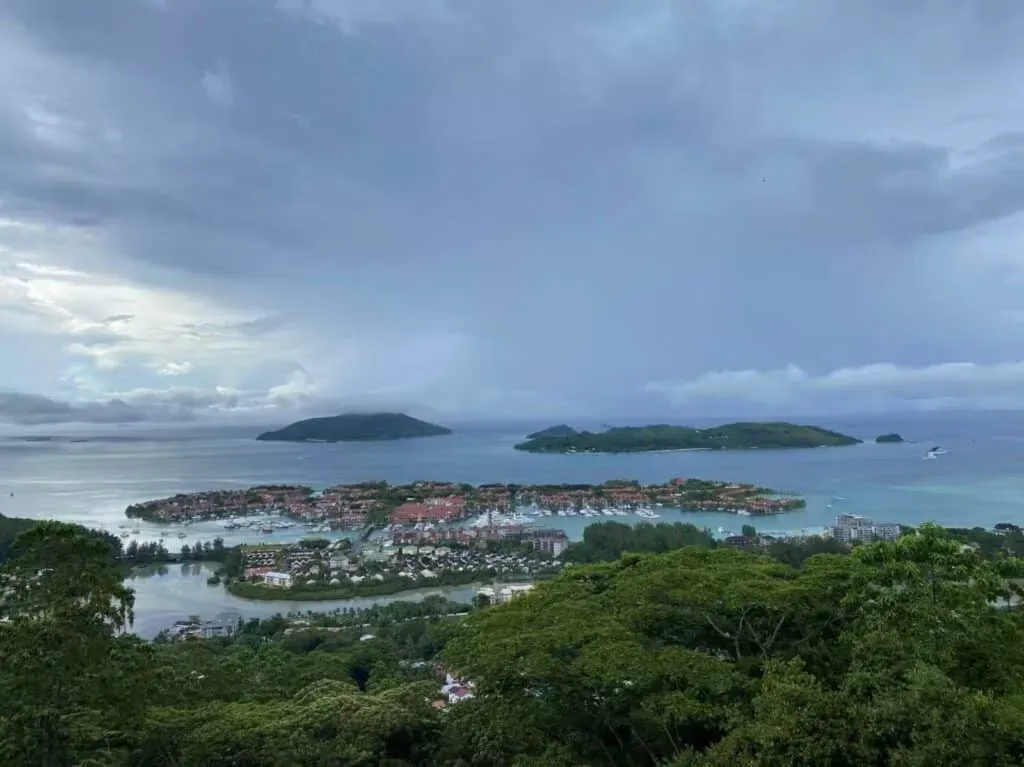 Panoramic view of Eden Island and nearby islands, surrounded by blue ocean and lush greenery under a cloudy sky in Seychelles.
