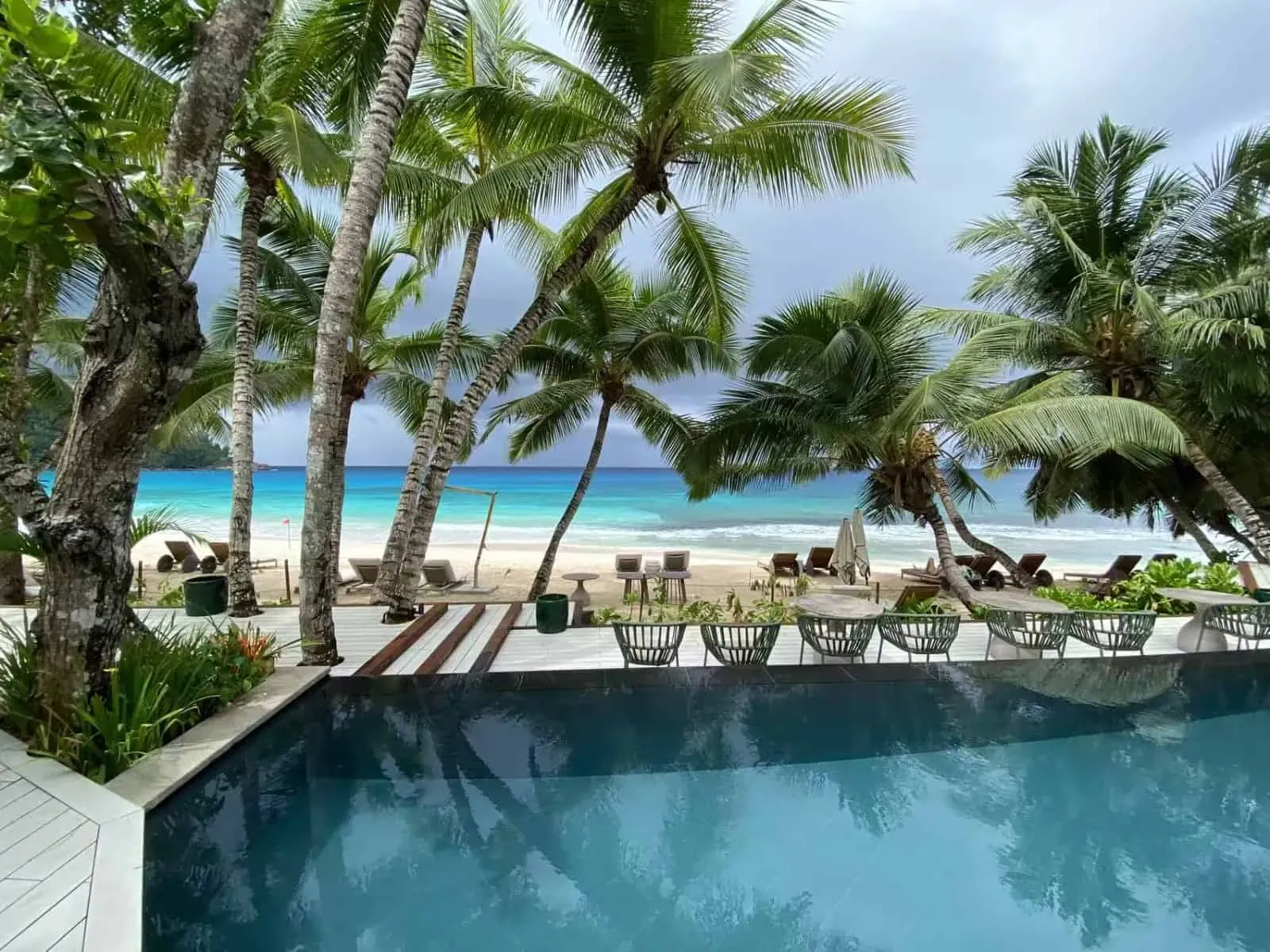 Luxurious tropical beach resort overlooking the ocean with palm trees, lounge chairs, and a pool, perfect for a relaxing vacation in paradise.